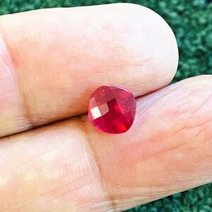 Könnte beinhalten: Ein tief roter Edelstein mit facettiertem Schliff. Der Edelstein ist herzförmig und hat eine polierte Oberfläche.