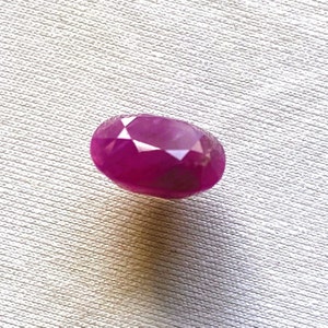 May include: A vibrant pink oval-shaped gemstone with a faceted cut.