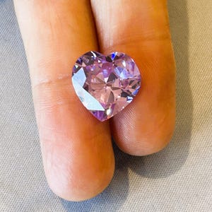 Może przedstawiać: Sercekształtny, jasnofioletowy kamień szlachetny z wieloma fasetkami.