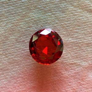 Pigeon Ruby, 12 mm round, AAAAA, Lab created, has gem quality hardness. Signature hand cut to the excellent brilliance. Coating free gem.