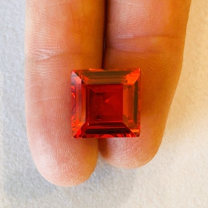 Może przedstawiać: Jaskrawoczerwony kwadratowy kamień szlachetny o fasetowanym szlifie.