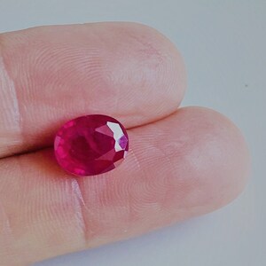 May include: A vibrant red oval-shaped gemstone with a faceted cut.