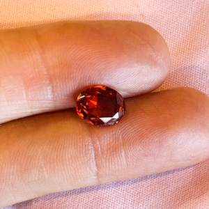 Może przedstawiać: Owalny kamień szlachetny w kolorze ciemno pomarańczowym z fasetkami.