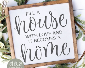 May include: A wooden framed sign with the text "Fill a house with love and it becomes a home" in a handwritten style. The sign is surrounded by a green and white leafy wreath. The words "Digital Cut File" are at the top.