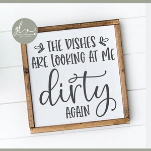 Puede incluir: Un diseño de archivo de corte digital con el texto "The dishes are looking at me dirty again". El diseño se muestra sobre un fondo blanco con un marco de madera y sobre un fondo blanco.