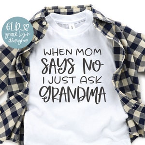 May include: White baby onesie with black text that reads "When Mom Says No I Just Ask Grandma". The onesie is folded and displayed on a plaid shirt and a pair of turquoise sneakers.