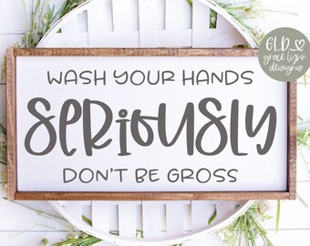 Könnte beinhalten: Ein rechteckiges Holzschild mit dem Text "WASH YOUR HANDS SERIOUSLY DON'T BE GROSS" in grauer Schrift. Das Schild ist von einem weißen Dekorationselement und Grün umgeben. Der untere Teil des Schildes trägt den Text "SVG - DXF - PNG - EPS".