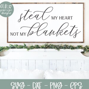 Pode incluir: Uma placa de madeira branca com caligrafia preta que diz "Steal my heart, not my blankets". A placa está pendurada acima de uma cama branca com uma cabeceira branca e roupa de cama branca.