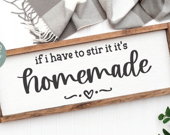 May include: A rectangular wooden sign with a white background and a dark brown frame. The sign features black text that reads, "if i have to stir it it's homemade" with a small heart icon centered below the word homemade.