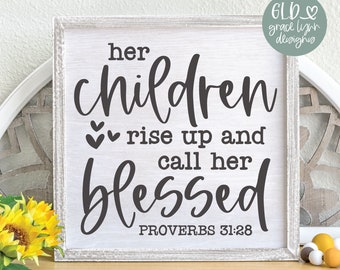 May include: A framed wooden sign with the text "her children rise up and call her blessed" in black script. The sign includes the Bible verse Proverbs 31:28. The sign is on a wooden surface with a floral arrangement.