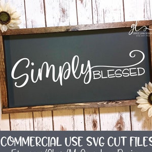 Könnte beinhalten: Ein dunkelgraues Holzschild mit einer weißen Aufschrift, die in kursiver Schrift "Simply Blessed" lautet. Das Schild ist mit einem dunkelbraunen Holzrahmen gerahmt.
