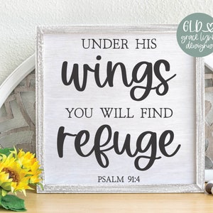 May include: A white wooden sign with black text that reads "Under His Wings You Will Find Refuge" and "Psalm 91:4". The sign is sitting on a wooden table with a decorative plate and yellow flowers.