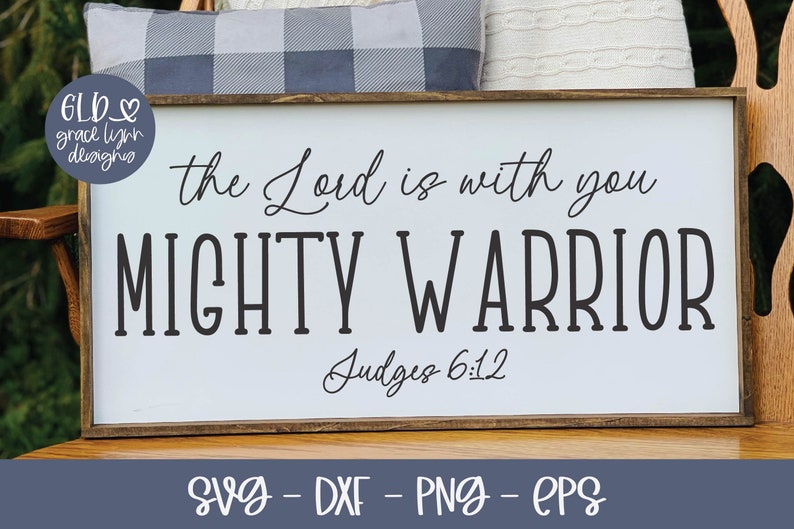 May include: A white wooden sign with the text "the Lord is with you MIGHTY WARRIOR Judges 6:12" in black lettering. The sign has a brown wooden frame.
