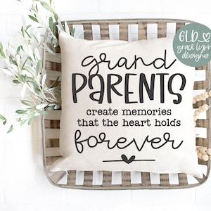 May include: A white pillow with black text that reads "grand PARENTS create memories that the heart holds forever" with a small heart at the end of the text. The pillow is sitting in a woven basket with a wooden bead garland.