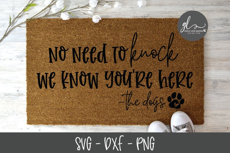 Pu&ograve; includere: Un tappetino da porta marrone con il testo "No Need to Knock We Know You're Here - The Dogs" in lettere nere. Un'impronta di zampa nera con un cuore all'interno &egrave; a destra del testo.