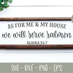 May include: A wooden sign with the text "AS FOR ME & MY HOUSE we will serve salmon ALASKA 24:7". The sign is on a white background with black and white checkered fabric and green foliage.