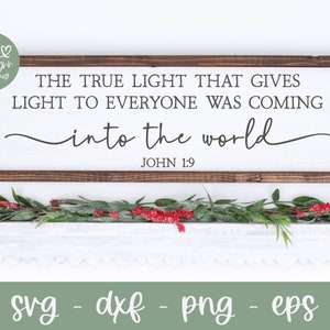 May include: A wooden sign with a white background and brown frame. The sign features the text "THE TRUE LIGHT THAT GIVES LIGHT TO EVERYONE WAS COMING into the world JOHN 1:9".