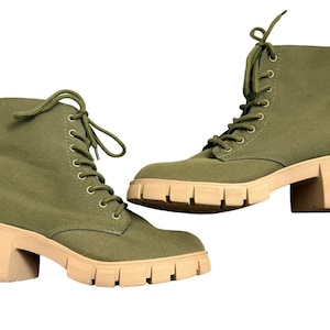 May include: A pair of olive green lace-up ankle boots featuring a canvas upper, matching green laces, metal eyelets, and a chunky, thick-soled beige block heel with a deep-tread lug pattern for traction and a sturdy, elevated silhouette.