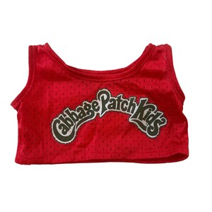 May include: A red mesh tank top with the words "Cabbage Patch Kids" in a white and green design. The tank top is a sleeveless style.