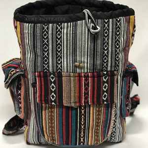 May include: A multi-coloured striped backpack with a black drawstring top and a small pocket on the front. The backpack has the text "ACHI AUSTRALIA" on the top.