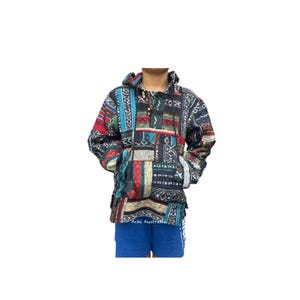 May include: A patchwork hoodie with a hood and a front pocket. The hoodie features a mix of colourful patterns in red, blue, black, and white. The garment has a drawstring at the neck and is made of a textured fabric.