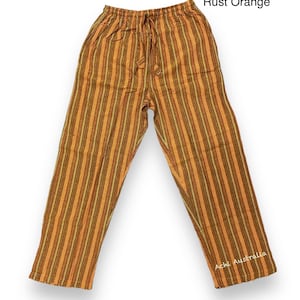 May include: Rust orange striped pants with a drawstring waist. The pants are made of a soft, comfortable fabric and have a relaxed fit. The pants are labeled "Achi Australia" on the bottom right leg.