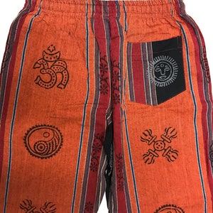 May include: Orange and maroon striped pants with a variety of printed symbols, including a yin yang, a sun, and an om symbol. The pants have a black pocket on the back.