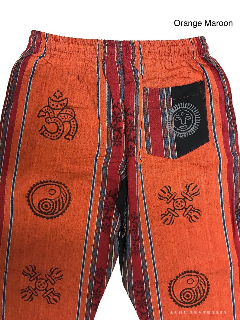 May include: Orange and maroon striped pants with a variety of printed symbols, including a yin yang, a sun, and an om symbol. The pants have a black pocket on the back.