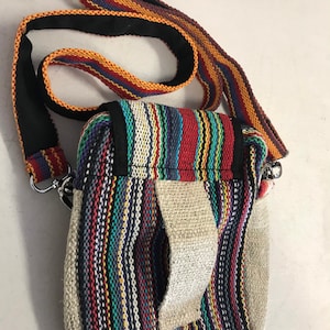 May include: A small, multi-coloured striped crossbody bag with a long adjustable strap. The bag has a flap closure and a small pocket on the front.