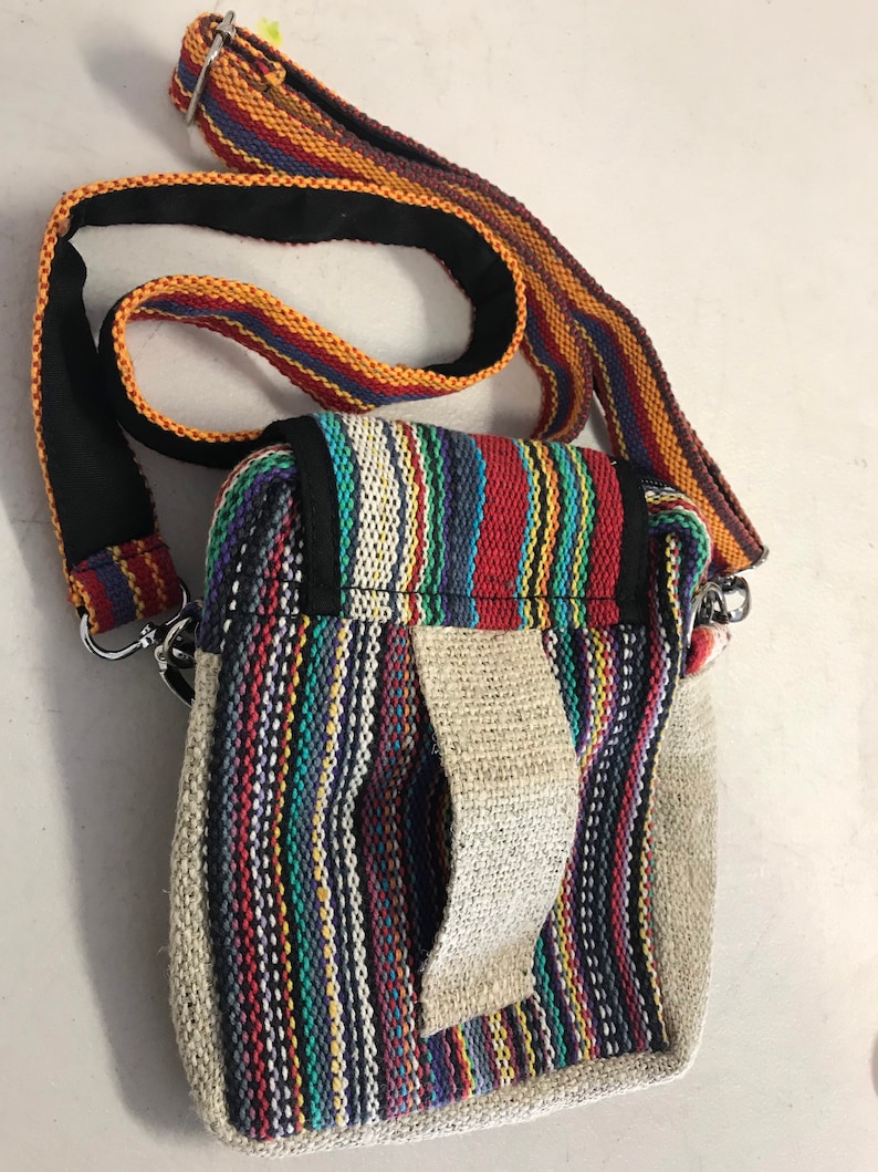 May include: A small, multi-coloured striped crossbody bag with a long adjustable strap. The bag has a flap closure and a small pocket on the front.