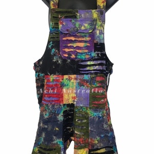 May include: Multicolored tie-dye overalls with distressed detailing and a patch pocket. The overalls are made of a patchwork of different fabrics and have a relaxed fit.