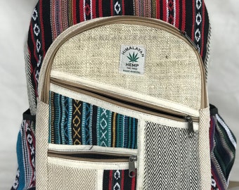 Puede incluir: Una mochila de cáñamo beige con detalles de tela estampada de colores. La mochila tiene dos bolsillos con cremallera en la parte delantera y una etiqueta que dice "Himalayan Hemp THC Free Made in Nepal".