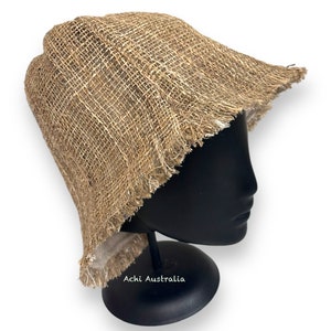 May include: A brown, woven, wide-brimmed hat with a frayed edge. The hat is on a black mannequin head.