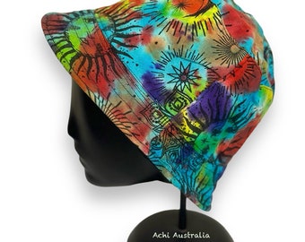 May include: A colorful bucket hat with a tie-dye pattern featuring suns and moons. The hat is on a black mannequin head and stand. The text "Sun & Moon" is above the hat and "Achi Australia" is below the stand.