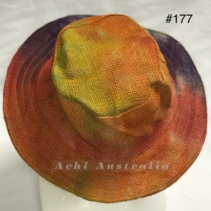 May include: A wide-brimmed straw hat with a tie-dye pattern in shades of orange, yellow, and purple. The hat has a #177 tag attached to it.