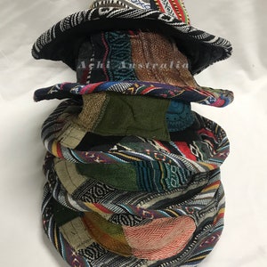 May include: A stack of four colourful, patterned bucket hats. The hats are made of fabric and have a variety of geometric and floral designs. The top hat has a black and white pattern with a red accent. #164