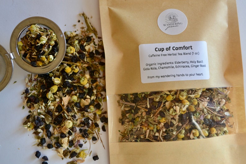 May include: A brown paper bag with a white label that reads "Cup of Comfort Caffeine Free Herbal Tea Blend (1 oz.) Organic Ingredients: Elderberry, Holy Basil Gota Kola, Chamomile, Echinacea, Ginger Root From my wandering hands to your heart."