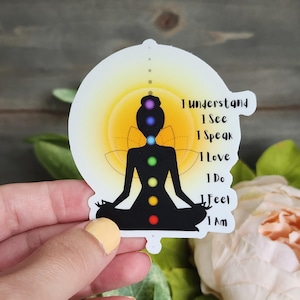 May include: A sticker featuring a black silhouette of a person in a seated yoga pose, with chakra colors and text. The background is a yellow and white gradient. Text on the sticker reads: "I Understand, I See, I Speak, I Love, I Do, I Feel, I Am."