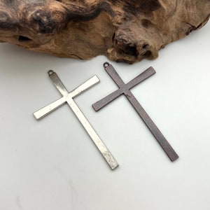 May include: Two metal cross charms, one silver and one copper, with a loop at the top for hanging.