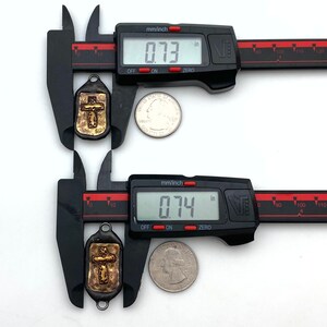 May include: Two gold-toned metal cross charms with a textured surface, measured with a digital caliper. The charms are approximately 0.73 inches and 0.74 inches in size.