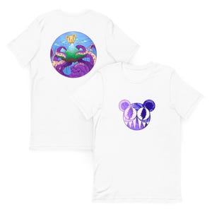 Puede incluir: Camisetas blancas con diseños gráficos únicos. Una camiseta presenta un diseño circular colorido con un pulpo, una isla y un oso. La otra camiseta muestra una cara de oso morado y azul con dientes afilados. Ambas camisetas son de manga corta.