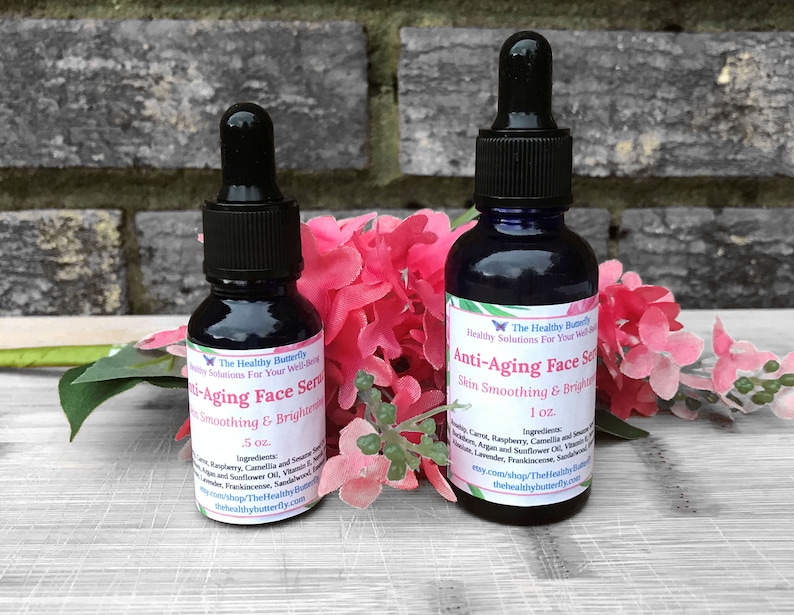 May include: Two dark blue glass bottles of anti-aging face serum with black droppers. The bottles are labeled with white text, including the brand name "The Healthy Butterfly" and the serum's purpose: "Skin Smoothing & Brightening."
