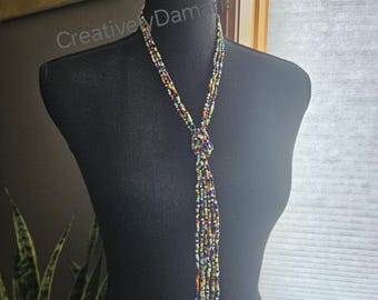 May include: A long, multi-strand beaded necklace with a knotted tassel. The beads are small and colorful, including shades of red, yellow, green, blue, and black.