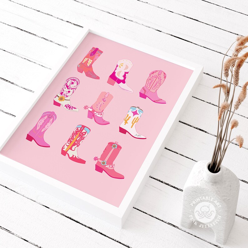 May include: A framed print featuring a collection of colorful cowboy boots in various shades of pink, red, and white. The boots are arranged on a pink background, creating a vibrant and stylish design. The print is in a white frame.