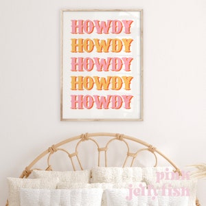 May include: A framed print with the word "HOWDY" repeated five times in a retro font. The word is in pink and orange, with a white background.