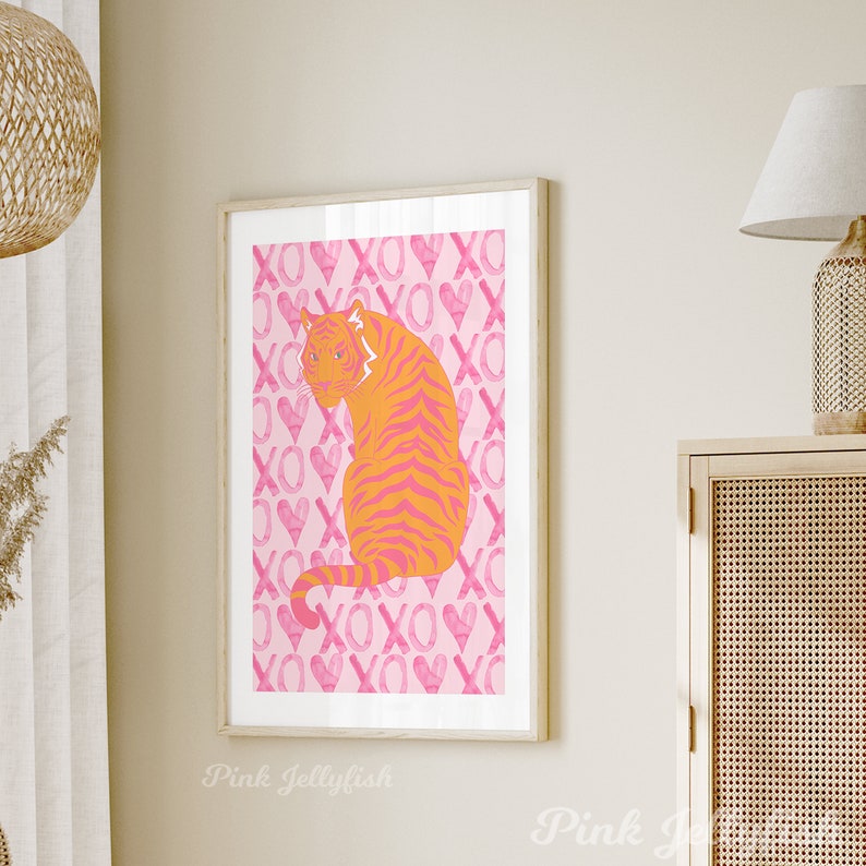 Op de afbeelding: Een illustratie van een roze en oranje tijger op een roze achtergrond. De achtergrond is bedekt met een herhalend patroon van roze harten en de letters XO.