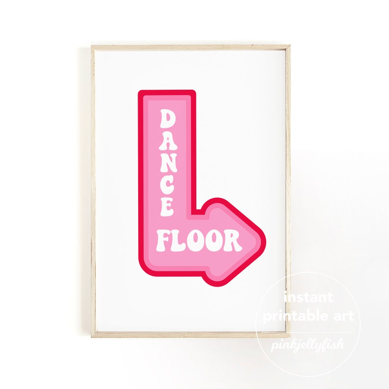 Pode incluir: Uma placa de seta rosa e vermelha com as palavras "Dance Floor" em texto branco. A placa est&aacute; emoldurada em uma moldura de madeira clara.