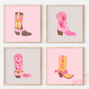 May include: Set of four printable art prints featuring pink, yellow, and brown cowboy boots with floral and geometric designs. The prints have a pink background and are framed in a light wood frame.