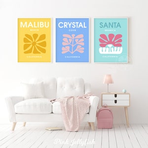 May include: Three minimalist art prints with abstract floral designs in yellow, blue, and turquoise. The prints feature the text "Malibu Beach California", "Crystal Cove California", and "Santa Monica California".