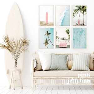 May include: A set of six framed prints with a beach theme. The prints feature palm trees, surfboards, a pink van, and ocean waves. The prints are arranged in a grid pattern on a white wall above a light-colored couch.